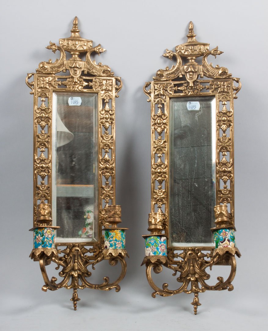 Pair of Classical style two-light sconces: each mirrored-back sconce with pierced brass frame with aldine dolphin and urn cornice, two candle lights with Longwy faience shafts, 23 in. L., 8 in. W.