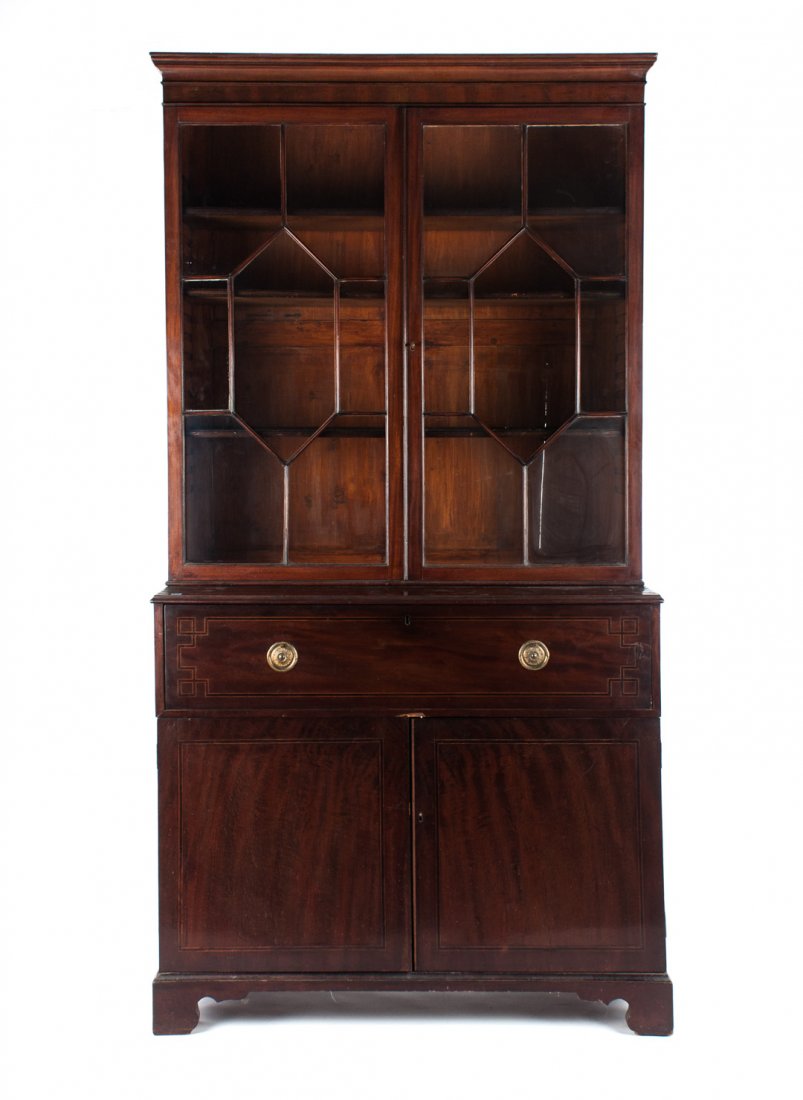 Regency mahogany butler's desk: circa 1815; with associated glazed panel bookcase top, single inlaid desk drawer over two inlaid cabinet doors, 93 in. H., 49 in. W., 22 in. D.