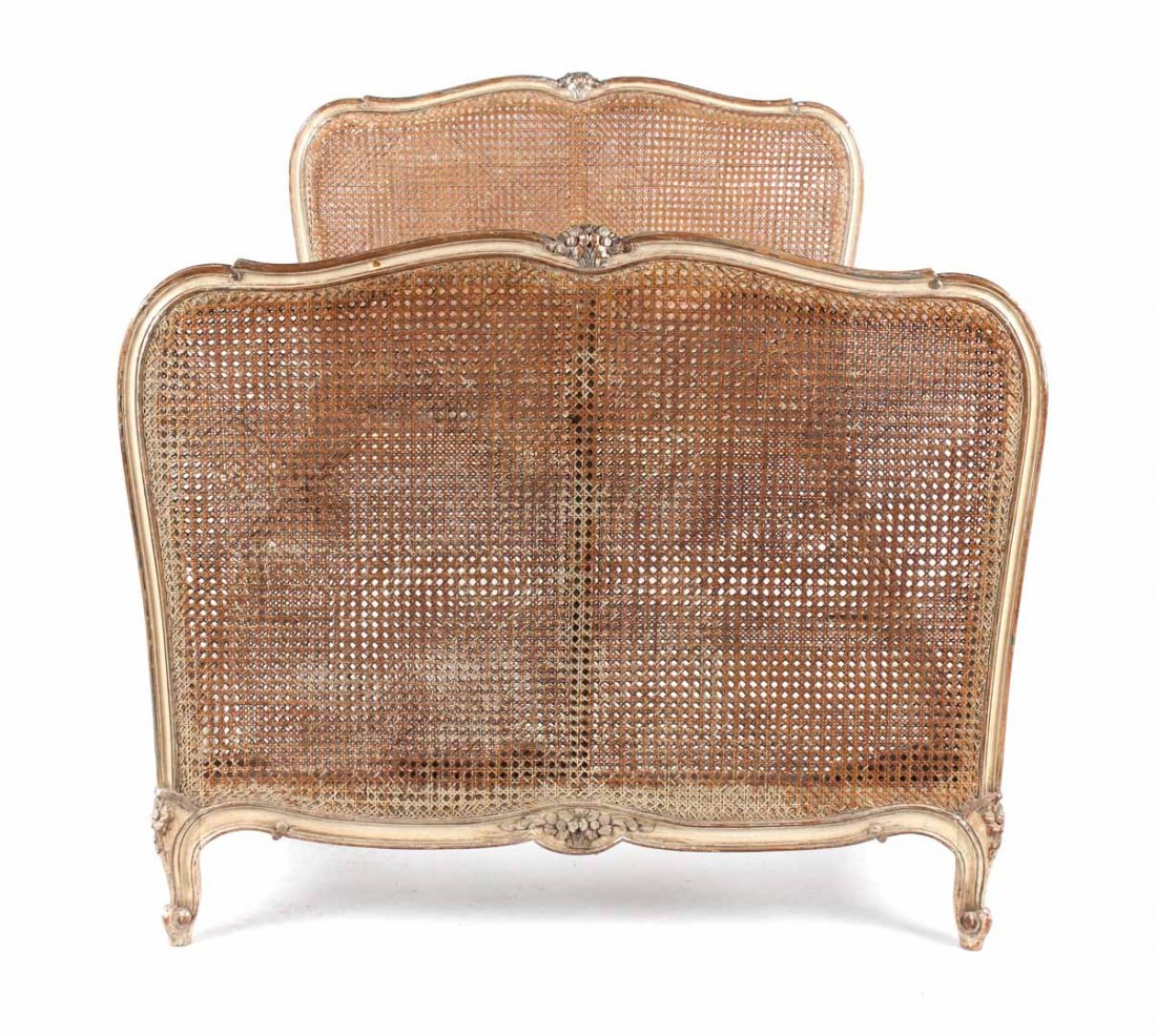 Louis XV style carved, painted, and caned daybed: exposed foliate carved, painted, and partial silvered head and foot boards with carved wooden side rails, 37 in. H., 44 in. W.