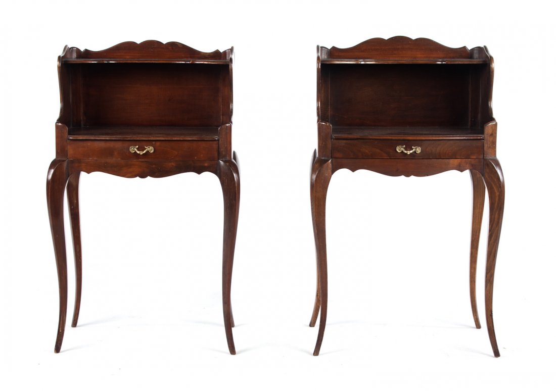 Pr French provincial style fruitwood side tables: 20th century; each with shaped shelf with raised gallery edge, open shelf beneath with drawer in shaped apron, cabriole legs, 29 1/2 in. H., 16 3/4 in. W., 12 in. D.