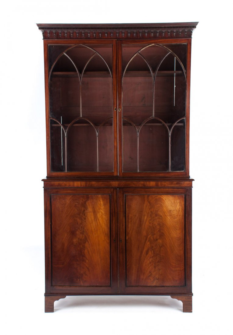 Gothic Chippendale style mahogany bookcase: 19th century; flat dentil-molded cornice, compartment with shelves enclosed by double astragal glass Gothic style doors, cabinet with shelves beneath enclosed by solid panel doors, straight bracket fe