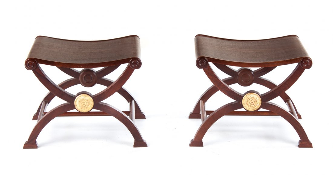 Pair of Classical style curule stools: each with solid saddle seat, X-form legs connected by stretchers, carved gesso giltwood rosettes, 17 1/2 in. H., 20 12 in. W., 17 in. D.