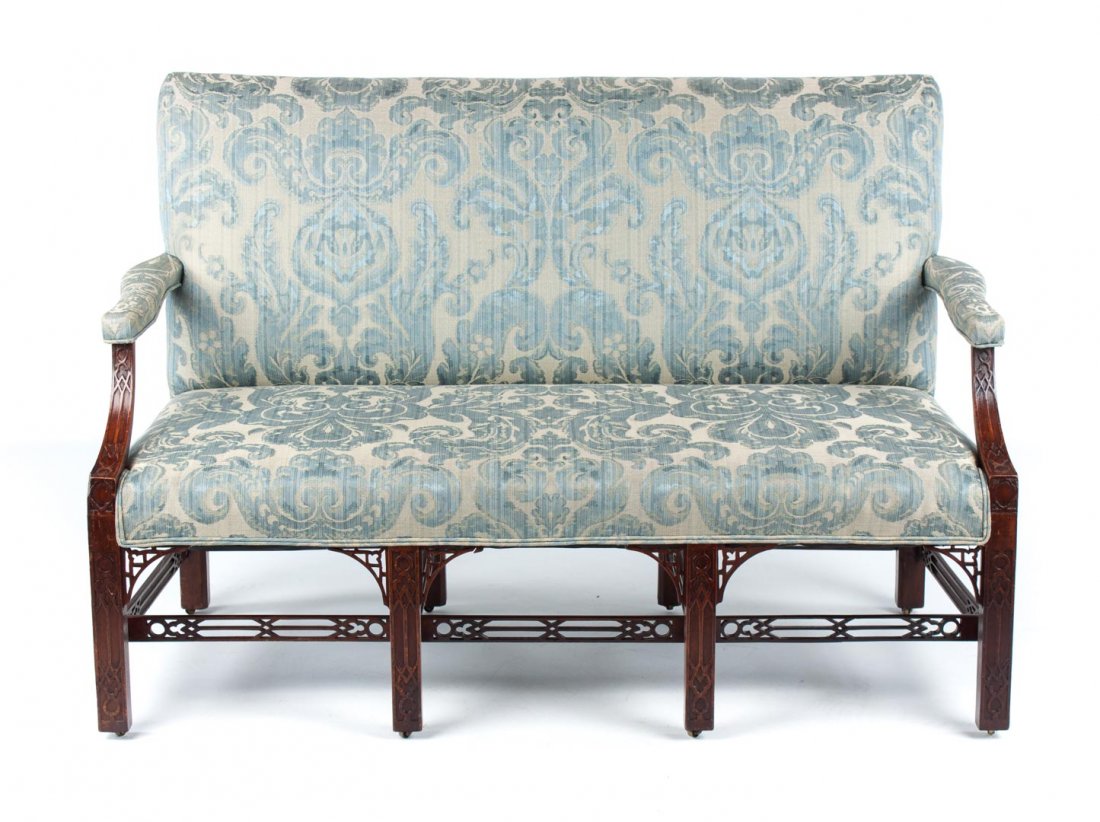 Chinese Chippendale style mahogany settee: 19th century; flat crest rail, upholstered panel back and seat over frame, blind fret carved recessed arms, eight straight fret carved legs with openworked spandrels and fretwork stretchers, 38 in. H.