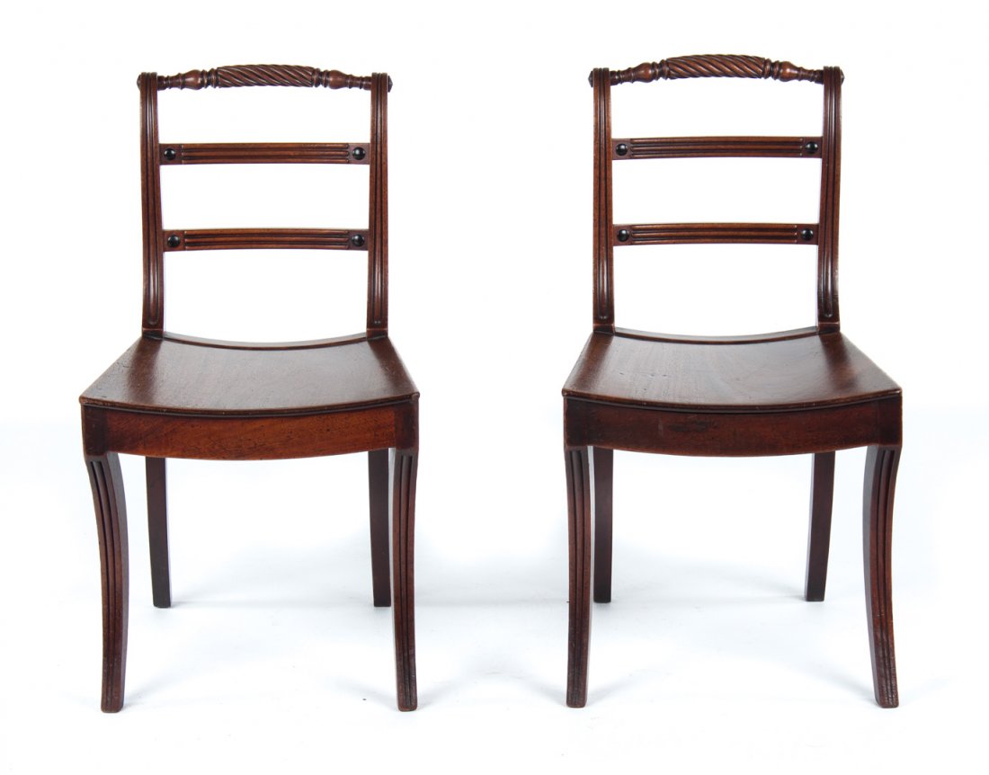 Pair of Regency carved mahogany side chairs: circa 1815; turned rolling pin crest rails and double horizontal splats, solid saddle seats, reeded sabre legs, 33 in. H., 18 in. W., 16 in. D.