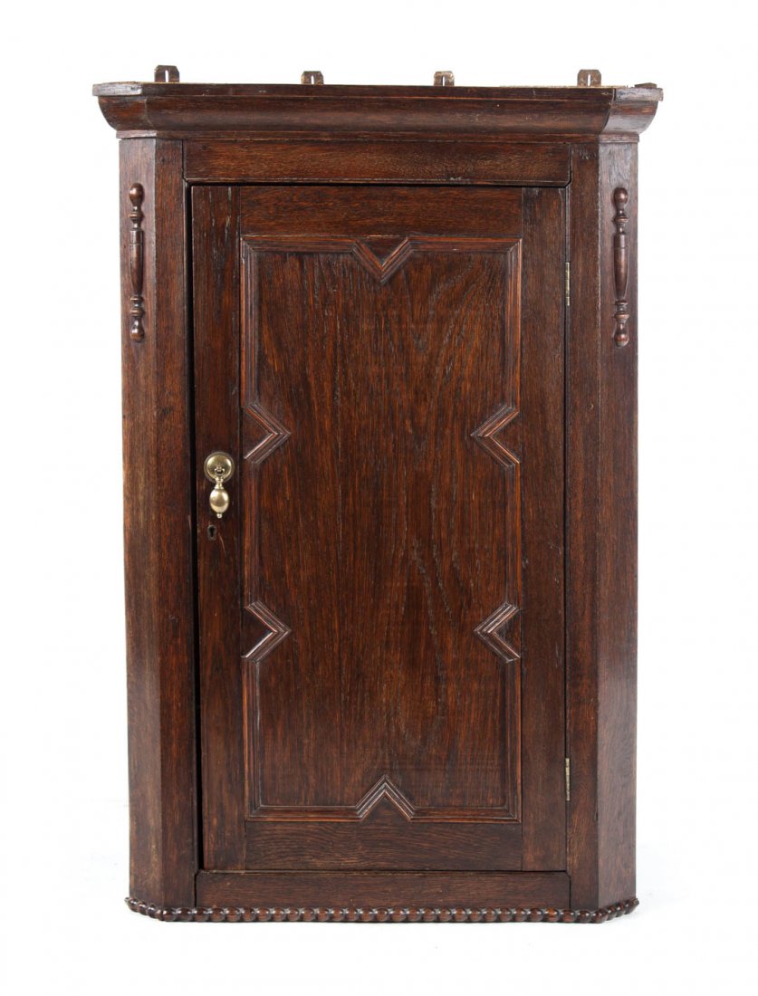 Elizabethan Revival oak hanging corner cupboard: 19th century; flat molded cornice, compartment with shaped shelves enclosed by solid panel door, bead molded base, split spindle appliquÃ©s, 39 1/2 in. H., 26 1/2 in. W., 16 in. D.