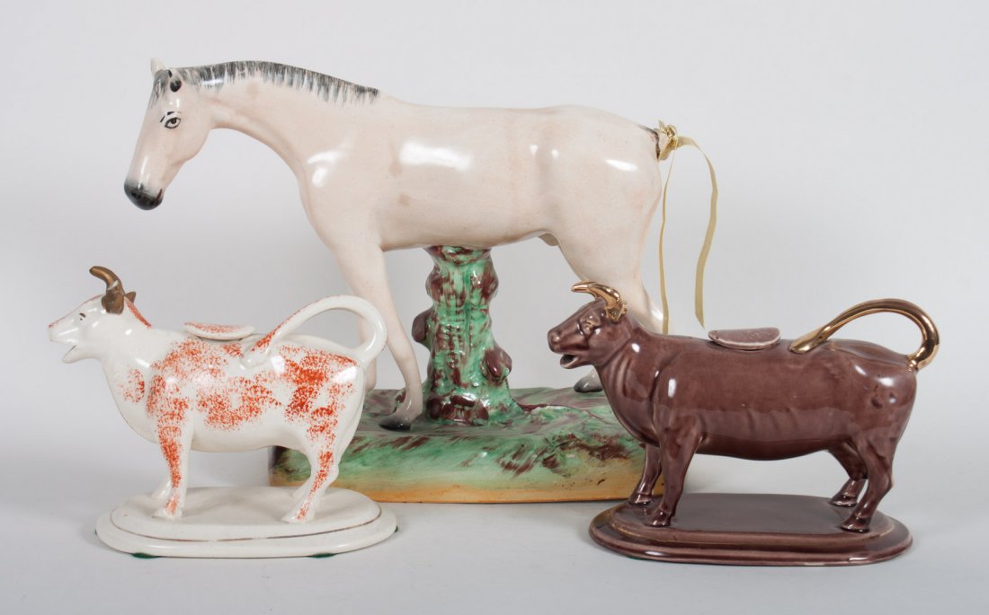 Staffordshire horse and two cow creamers: early 20th century; horse standing in meadow, 9 in. H., sponge decorated cow creamer, and a brown glazed cow creamer, approx. 5 in. H.