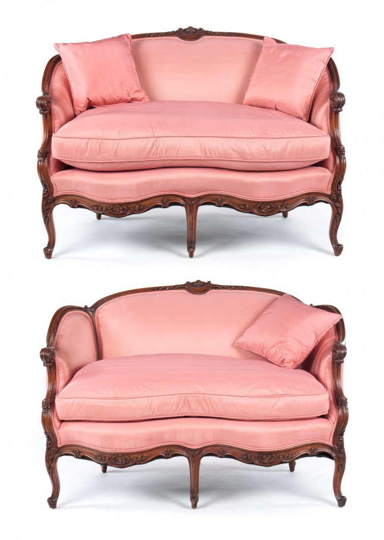 Pair of Louis XV style carved beechwood settees: 20th century; floral and foliated carved exposed crest rail, upholstered panel back, orielles, and seats with loose down-filled seat cushions, three cabriole front legs with foliate carved apron, 33 i