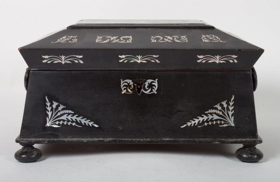 Victorian ebonized wood sewing box: second half-19th century; sarcophagus form with mother-of-pearl foliate and thistle inlay, fitted removable compartmental tray, on bun feet, 7 in. H., 12 in. Diam., 9 in. D.