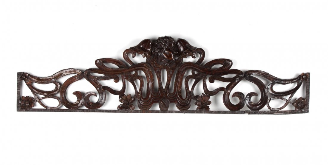 Art Nouveau carved wood cornice or valance: late 19th century; with classical carved profile head, floral rosettes, and reticulated scrolled decoration, 14 in. H., 56 in. L.
