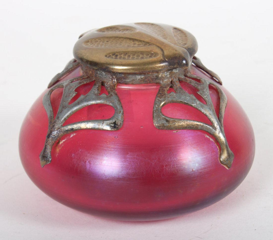 Art Nouveau brass-mounted art glass inkwell: possibly Loetz, early 20th century; iridescent cranberry glass with metal mounted decoration, hinged brass lid , 2 1/2 in. H., 3 1/2 in. Diam.