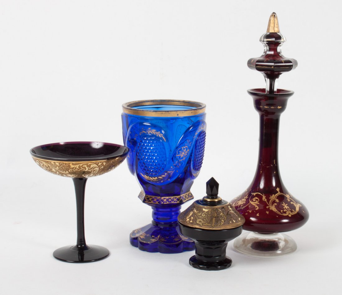 Four Bohemian colored glass articles: early 20th century; includes: cobalt goblet, cranberry decanter, amethyst and gilt decorated wine stem, and vanity box, 3 to 10 in. H.