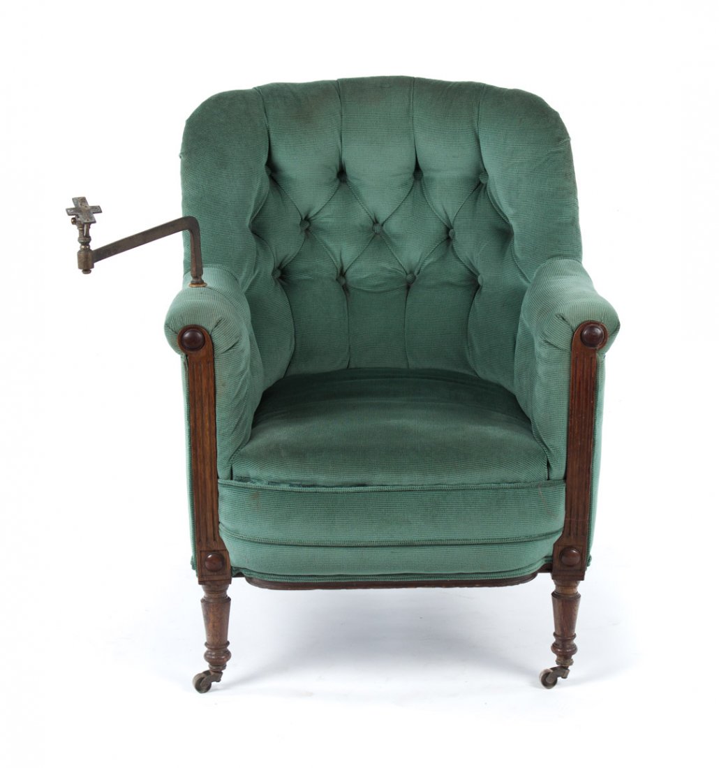 Edwardian upholstered oak library chair: late 19th century; button upholstered back over frame with exposed carved arm facings and round-turned legs, adjustable swivel brass book armature, 37 in. H., 28 in. W., 31 1/2 in. D.