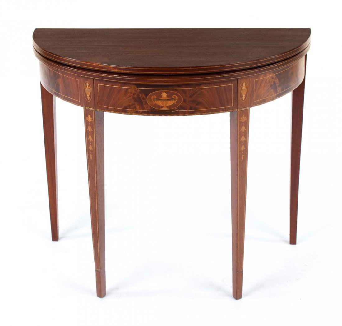Federal style inlaid mahogany games table: 20th century; hinged half-round leaf, banded, stringer, and urn inlaid apron, four straight tapered legs with bellflower inlay, 30 1/4 in. H., 36 in. W., 18 in. D.