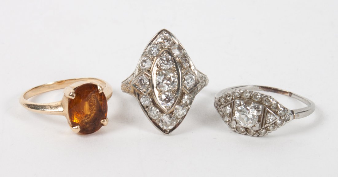 Two Art Deco platinum & diamond rings: one presenting a diamond about 30 pts., size 6, 2.7 g.; the other with a cluster of small diamonds in a marquise-shaped setting, size 4 1/4, 3.8 g.; together with a 14K gold topaz ring, size 5, 2.7 g.