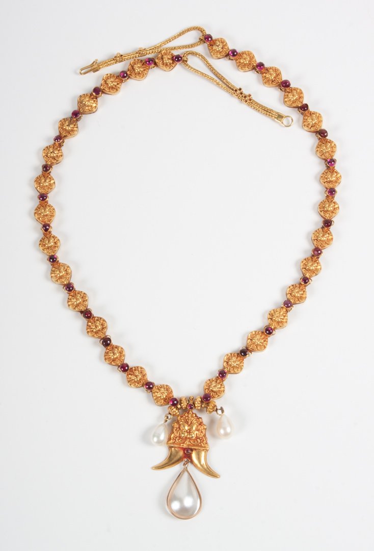 Indian Mughal style gold necklace: composed of 30 hollow gold beads modeled as lion's heads on foliate background, each set with red cabochon, centering a matching larger bead with horn-like projections, enhanced with mabe pearl drops;