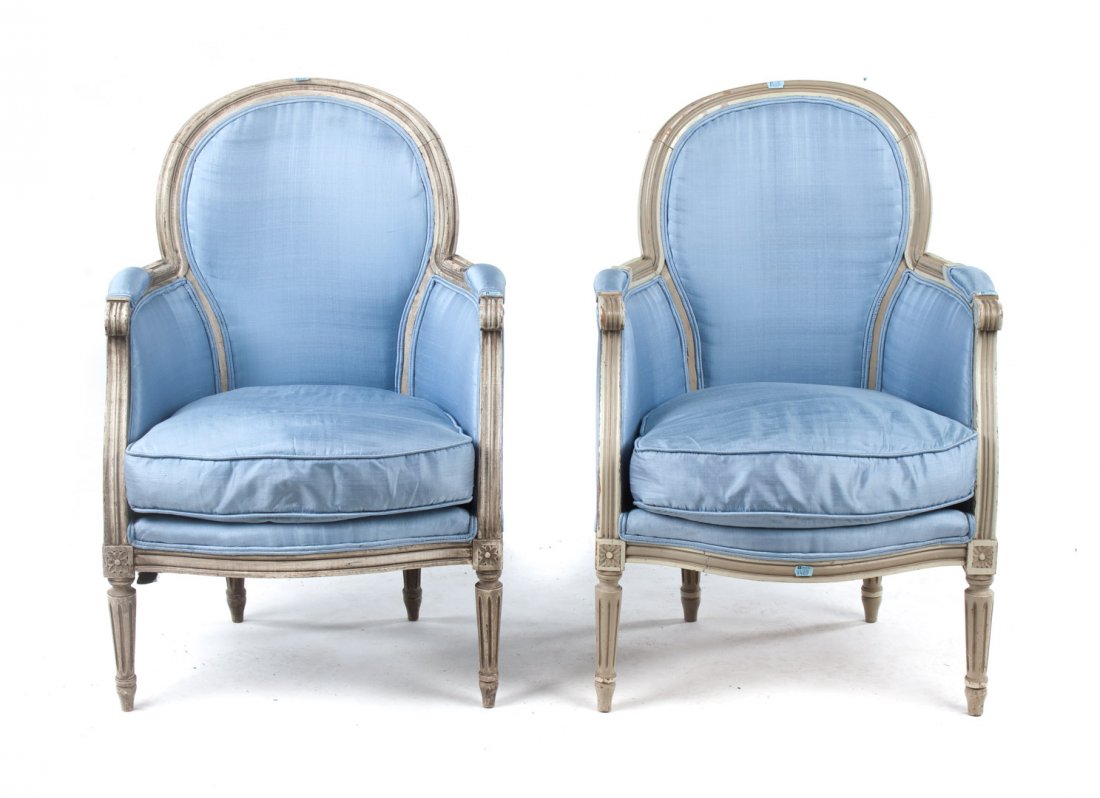 Pair of Louis XVI style upholstered bergeres: 20th century; carved exposed painted frames with upholstered backs, arms, and loose seat cushions, straight tapered and fluted legs, 34 in. H., 23 in. W., 17 in. D.