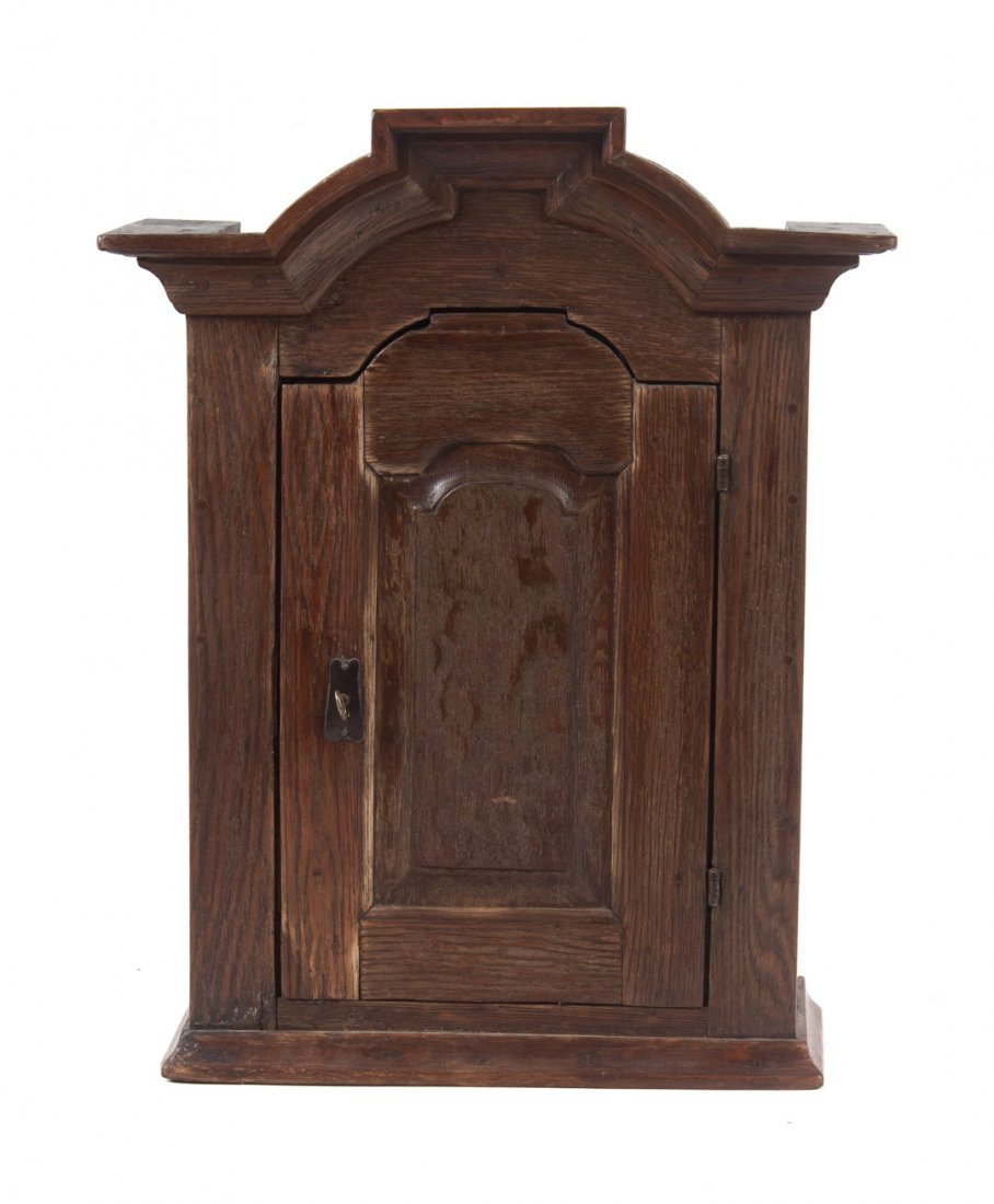 Georgian vernacular oak hanging cupboard: 18th century; heavily molded cornice, compartment with shelves enclosed by arched panel door, molded base, 27 1/4 in. H., 21 1/2 in. W., 10 in. D.
