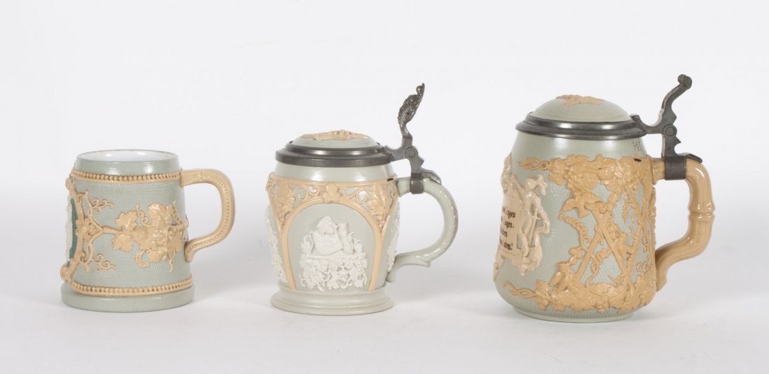 Three Villeroy & Boch salt glazed stoneware steins: early 20th century; two pewter-mounted steins with grapevine relief and vignettes of drinkers, 5 1/2 and 6 in. H., and similar tankard, 3 1/2 in., all with stamp marks