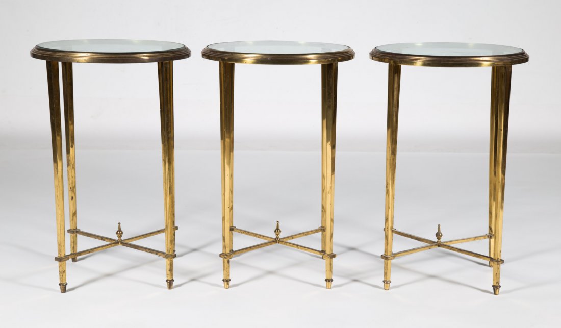 3 Neoclassical style brass and glass side tables: circular form with stretcher base, 24 in. H., 16 in. Diam.
