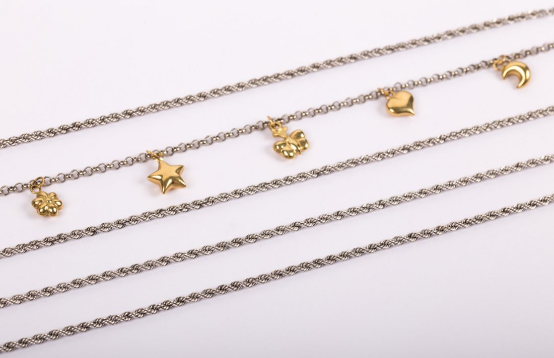 A Platinum & Gold Charm Bracelet: platinum rolo link charm bracelet with five 18K gold charms and an 18K gold clasp; together with four platinum rope chain bracelets