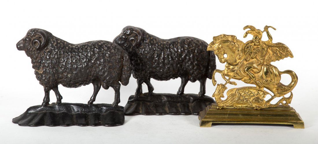 Three figural doorstops: 20th century; brass St. George and the Dragon doorstop, and a pair of cast iron ram doorstops, 8 in. H.