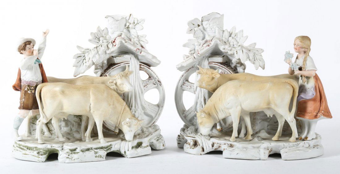 Pr of German painted bisque porcelain spill vases: each modeled as peasant boy and girl with two cows by a mill, 8 in. H., 8 1/2 in. W.