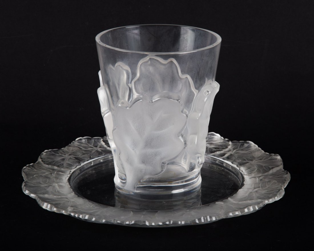 Lalique tumbler & wine bottle coaster: tumbler with partially frosted oak leaf decoration, 4 1/2 in. H., and wine bottle coaster with partially frosted leaf border, 8 1/2 in. Diam.