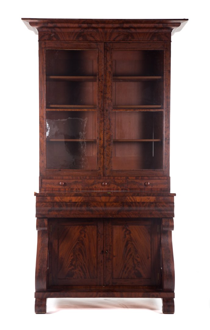 American Restoration mahogany secretary bookcase: circa 1830; flat molded cornice, upper case has compartment enclosed by double glass panel doors, long ogee molded drawer in lower case with compartment beneath enclosed by double solid panel doors, v