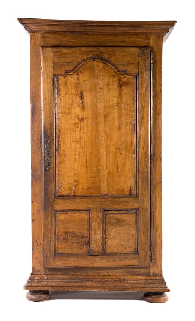 French walnut armoire: circa 1700; molded cornice, compartment with slides enclosed by solid panel door, heavily molded base, bun feet, 83 in. H., 46 in. W., 27 in. D.; Property from the Estate of Barbara Mertz