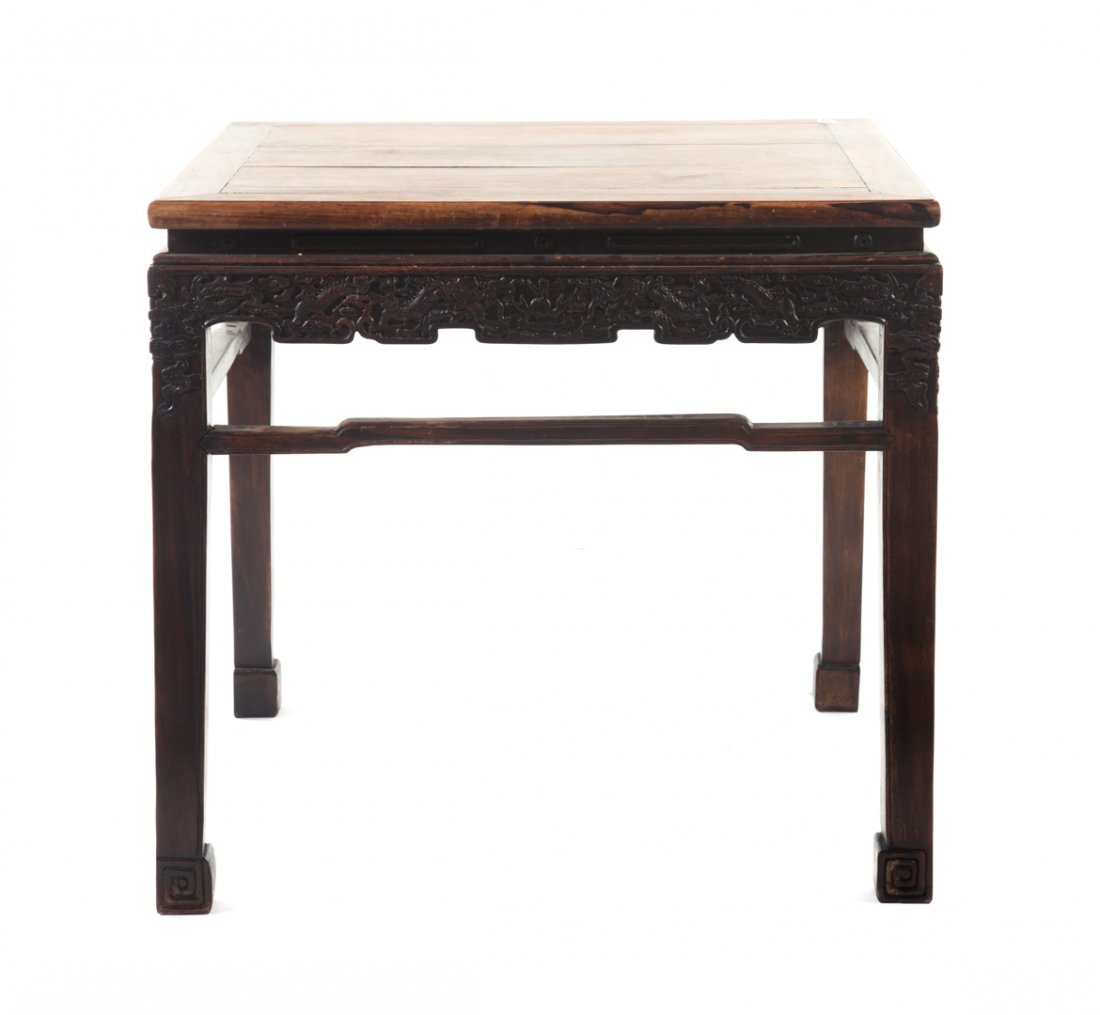 Chinese carved hardwood table: 20th century; flat top with molded edge, carved dragon apron, shaped stretchers, square legs with hoof feet, 33 1/2 in. H., 35 1/4 in. W., 35 1/4 in. D.