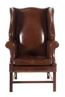 Hickory Chair George III style mahogany wing chair: mid-20th century; serpentine crest rail, brass studded leather upholstered back, arms and loose seat cushion, straight legs connected by "H" stretchers, 44 1/2 in. H., 30 1/2 in. W., 24 1/2 in. D.