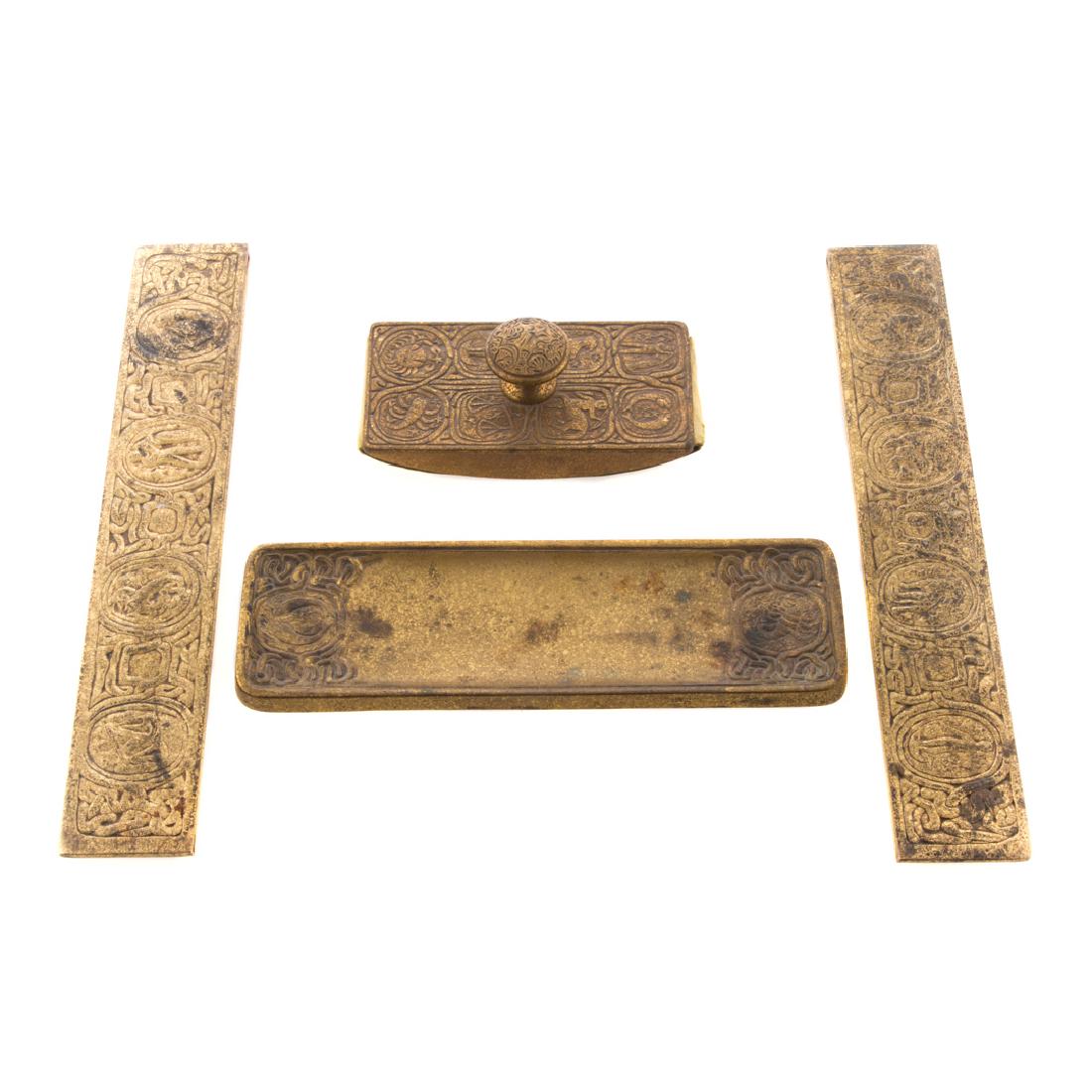 Tiffany gilt bronze Zodiac partial desk set: first quarter-20th century; including: pair blotter ends, impressed "Tiffany Studios New York 954", 12 in. L., 2 in. W., rocking blotter, impressed "Tiffany Studios New York 990", 5 1/2 in. L. and pen