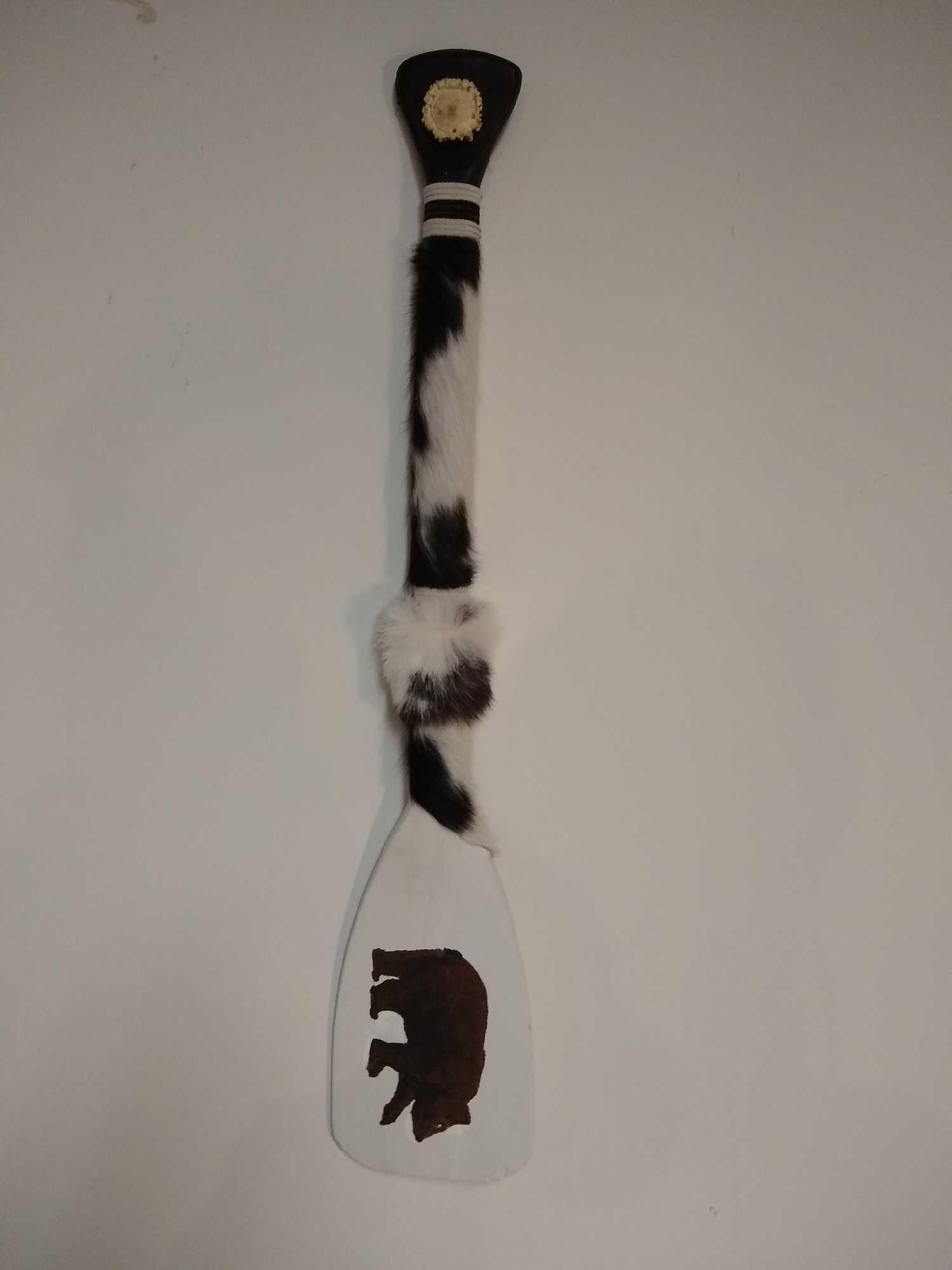 Paddle with Black Bear Painting: Paddle with Black Bear Painting crafted with cowhide, deer pedicle and other fur. 30" long. Comes with hook to hang on the wall.