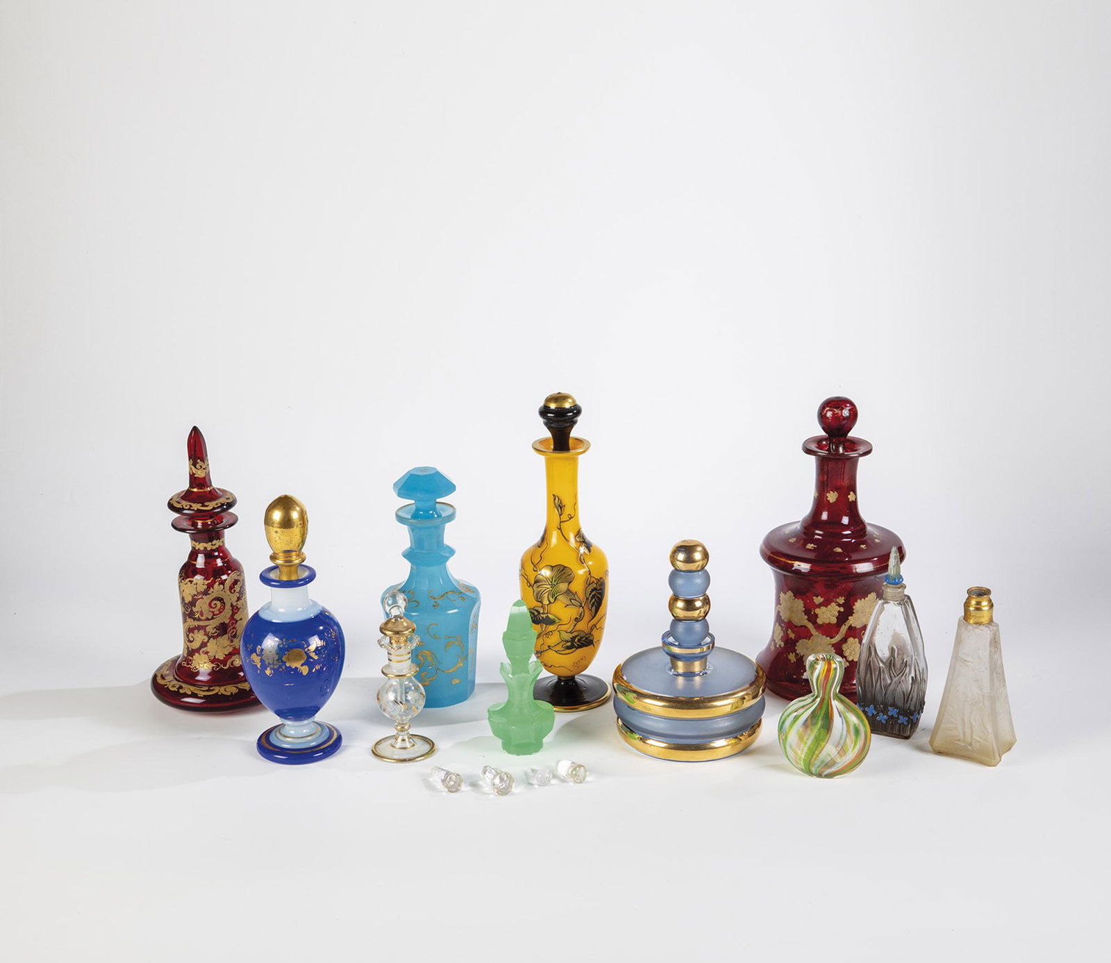 Konvolut: Elf Flakons, vier StÃ¶psel: Konvolut: Elf Flakons, vier StÃ¶psel 19. / 20. Jh. Farbloses, teils farbiges Glas, u. a. mit Dekor in Schwarzlot, Polier- und Reliefgold. Teils best.. H. 11 - 23,5 cm (Flakons); H. 2 - 3 cm (StÃ¶p