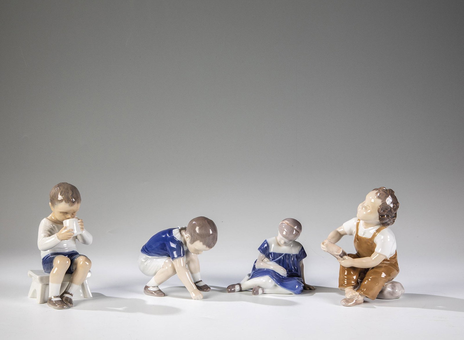 Vierteiliges Konvolut: Vierteiliges Konvolut Bing & GrÃ¸ndahl, Kopenhagen, 1966-1982 Vier sitzende und kniende Kinderfiguren. Unterglasurbemalung. Unterseite bez.: in Unterglasur grÃ¼n-blauer Manufakturstempel, Modell-N
