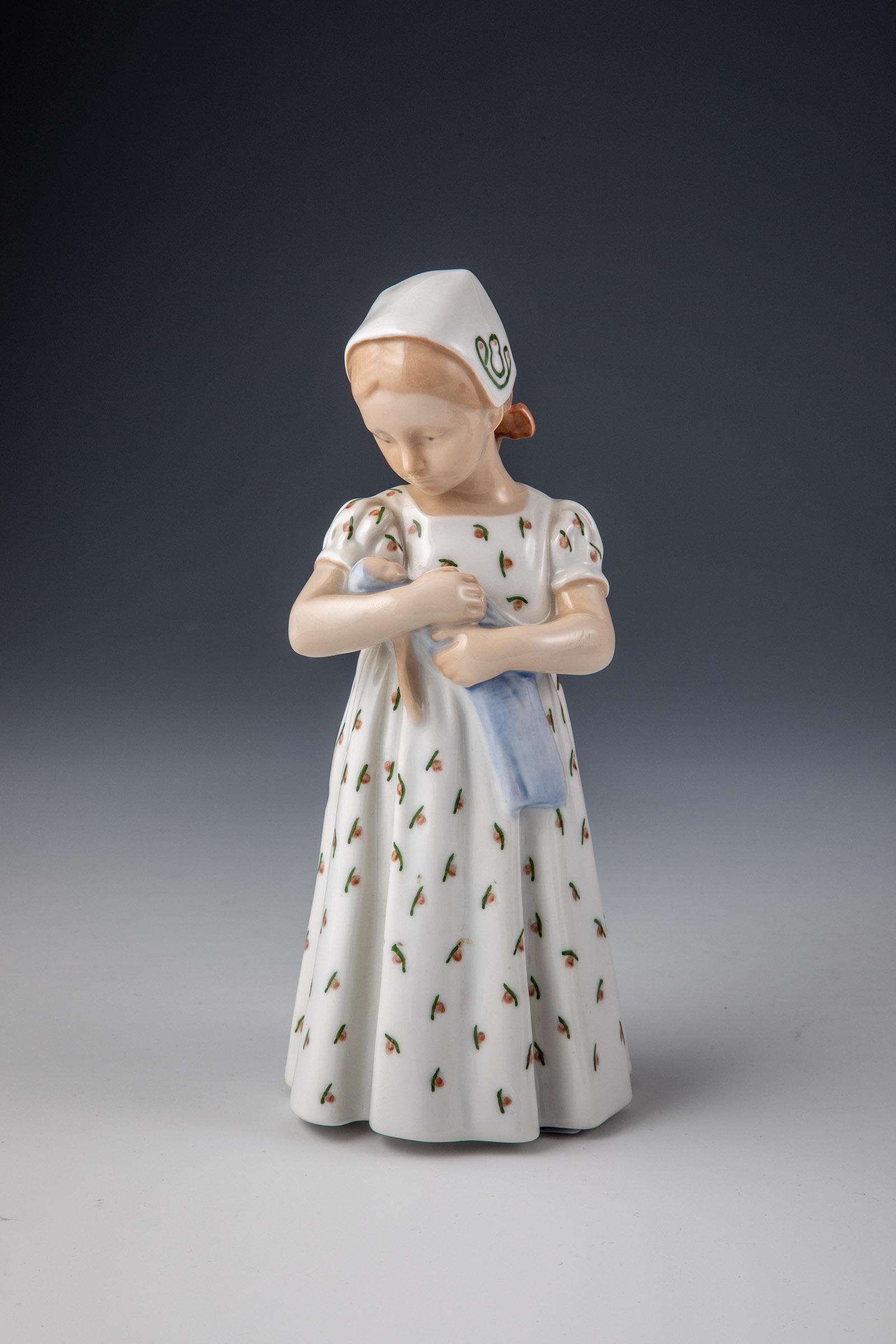 Mädchen mit Puppe: Mädchen mit Puppe Bing & Groendahl, Kopenhagen, 1948-1951 Stehendes Mädchen mit Puppe in den Armen. Zarte Unterglasurbemalung. Unterseite bez.: Unterglasurgrüne Stempelmarke, 1721 und BH (in Unterg