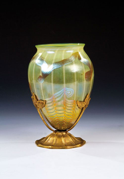 An iridescent glass vase with mount Louis Comfort T: English: An iridescent glass vase with mount Louis Comfort Tiffany, New York, circa 1900 Light-green glass with underlay and trails of yellow. Engraved mark: "L 2410". Mount with leafs and mark: "TIFF