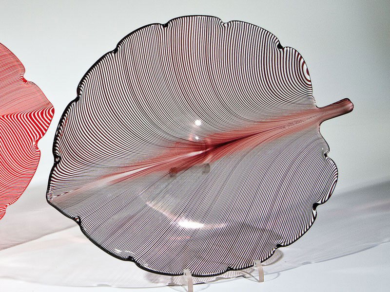 Blattschale ''Foglia'': Blattschale ''Foglia'' Tyra Lundgren (Entwurf), Venini, Murano, um 1936 Farbloses Glas mit eingeschmolzenen violetten Fäden ('mezza filigrana'). In Vibrogravur bez.: venini italia 85. L. 28 cm Lit.: