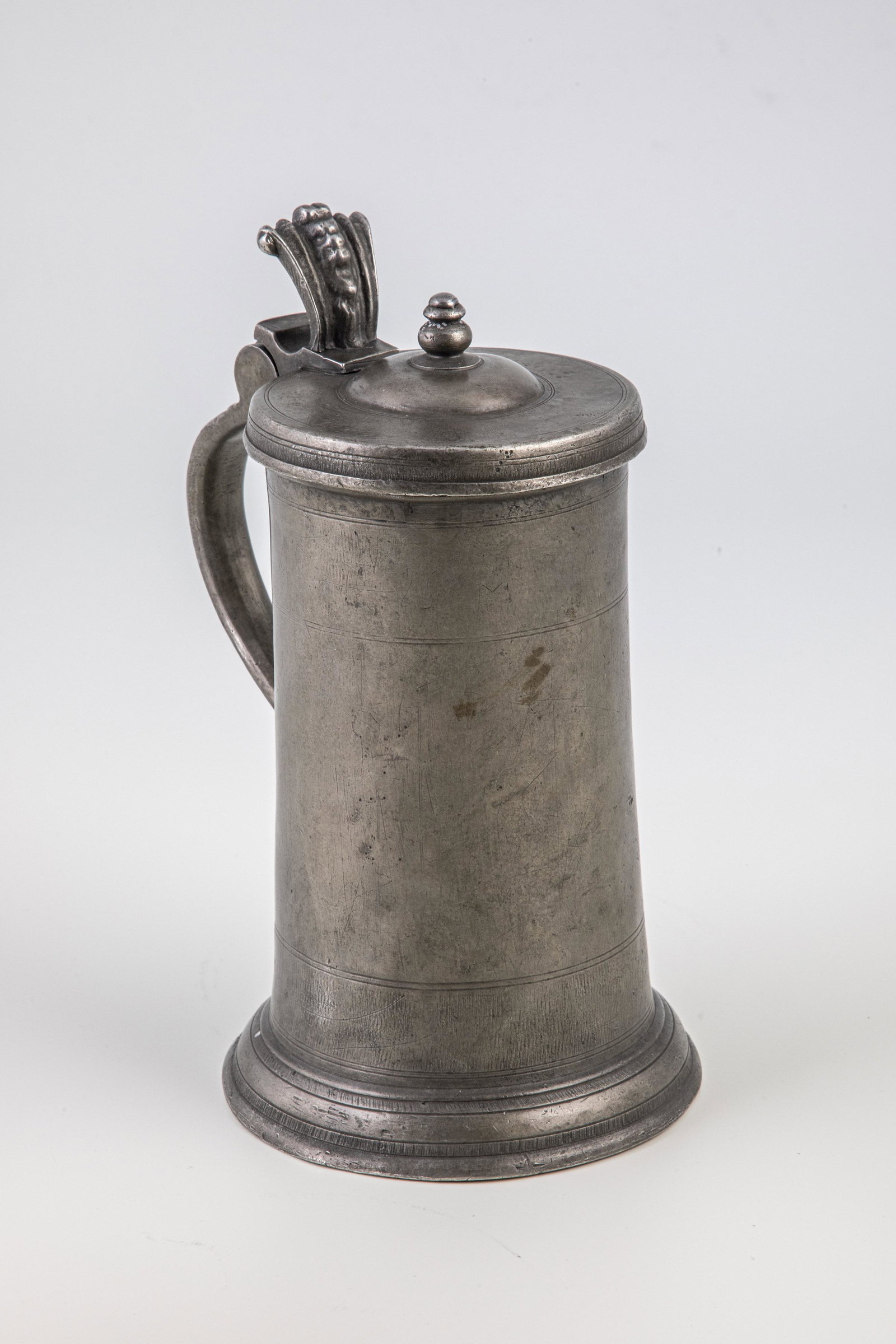 Pewter wine jug: Pewter wine jug Transylvania, Sibiu, master C.Ã–.R., 17th century. Stand, mantle and lid decorated with roughened borders. On lid turreted knob and helmet bush pusher. Relief handle with pewter cas
