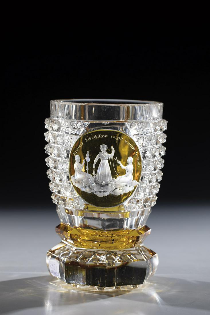 Mug with the parzen: Goblet with the Parzen Bohemia, mid-19th century. Colorless glass, cut, partially stained yellow. Frontal high cut medallion with deep cut decor: the three parzen, above inscription ''Spinnet bedachts