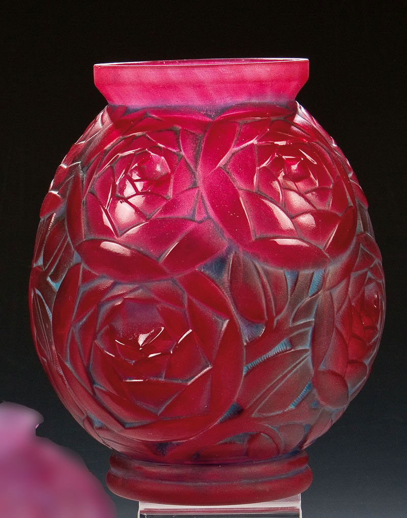 Vase mit Rosenblüten: Vase mit Rosenblüten Pierre d'Avesn, Croismare, um 1930 Farbloses Glas, mit rotvioletter Pulvereinschmelzung, in die Form gepreßt. Umlaufend rapportierender stilisierter Reliefdekor: Zweige mit Rose