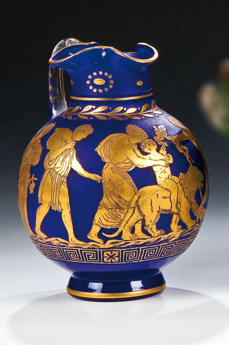 Krug ''Etrusk'': Krug ''Etrusk'' Loetz Wwe., Klostermühle, 1928 Farbloses, kobaltblau unterfangenes Glas. Reliefiert geätzter und vergoldeter Dekor: antikisierender Figurenfries. Henkel in farblosem Glas. H. 18,5 cm