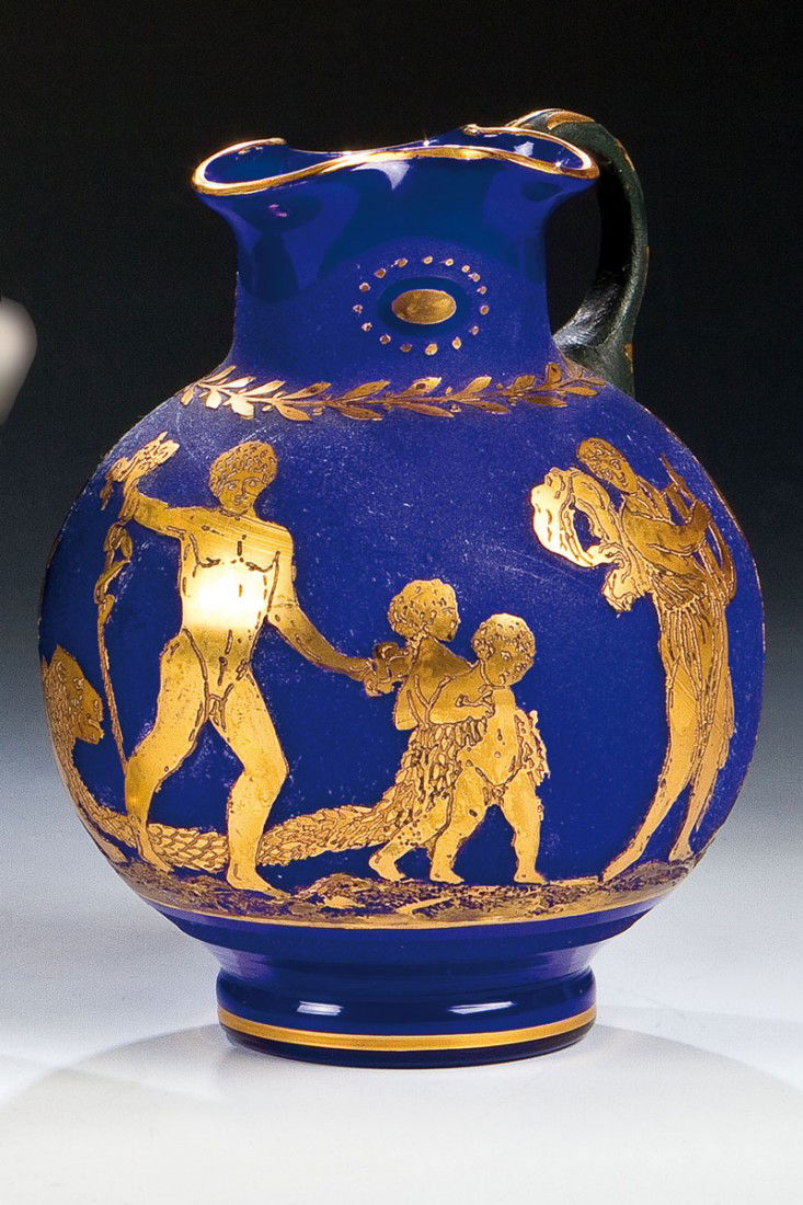 Krug ''Etrusk'': Krug ''Etrusk'' Loetz Wwe., Klostermühle, 1928 Farbloses, kobaltblau unterfangenes Glas. Reliefiert geätzter und vergoldeter Dekor: antikisierender Figurenfries. Henkel in Dunkelgrün. H. 18,5 cm Li