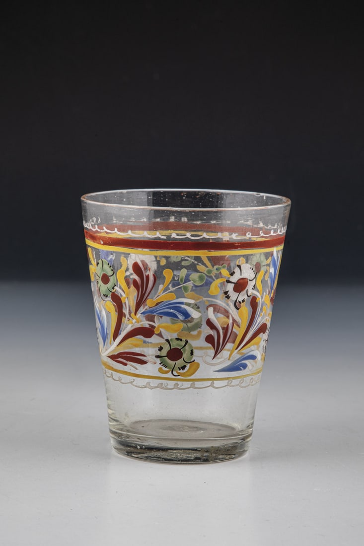 Cup: Mug South German or Switzerland, 18th century Colorless glass with tear. On the conically widened wall, circumferential flower border in colorful enamel painting. H. 9.5 cm