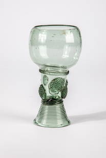 Roemer: Roman German, 17th century Green glass with demolition. Woven foot. Shaft open at the top with two rows of offset applied berry nubs. Thread pinched at the base of the compressed, bulbous cuppa. H. 11