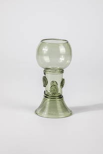 Roemer: Roman German, 17th century Light green glass with demolition. Spun foot, shaft open at the top with offset application of berry nubs. Below the bulbous cuppa, pinched thread is placed. H. 11.5 cm