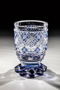 Foot cup: Footcup New World, M. 19th century Colourless glass with cobalt blue overlay. Eight-pass foot. Wall with high-cut squares, these with notched and stone cut decor. Contrasting lip margin. H. 12.5 cm. L