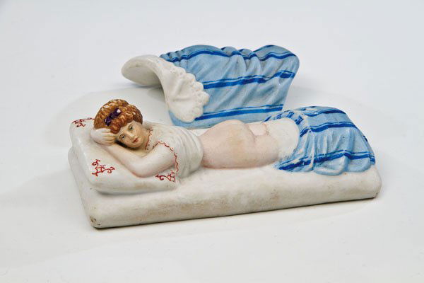 Erotische Figur in Form einer liegenden Dame: Erotische Figur in Form einer liegenden Dame Moskau, Porzellanmanufaktur Gardner, Ende 19. Jh. Biskuitporzellan. Auf rechteckigem, in Form eines Bettes gearbeitetem Sockel liegende Dame mit entblöste