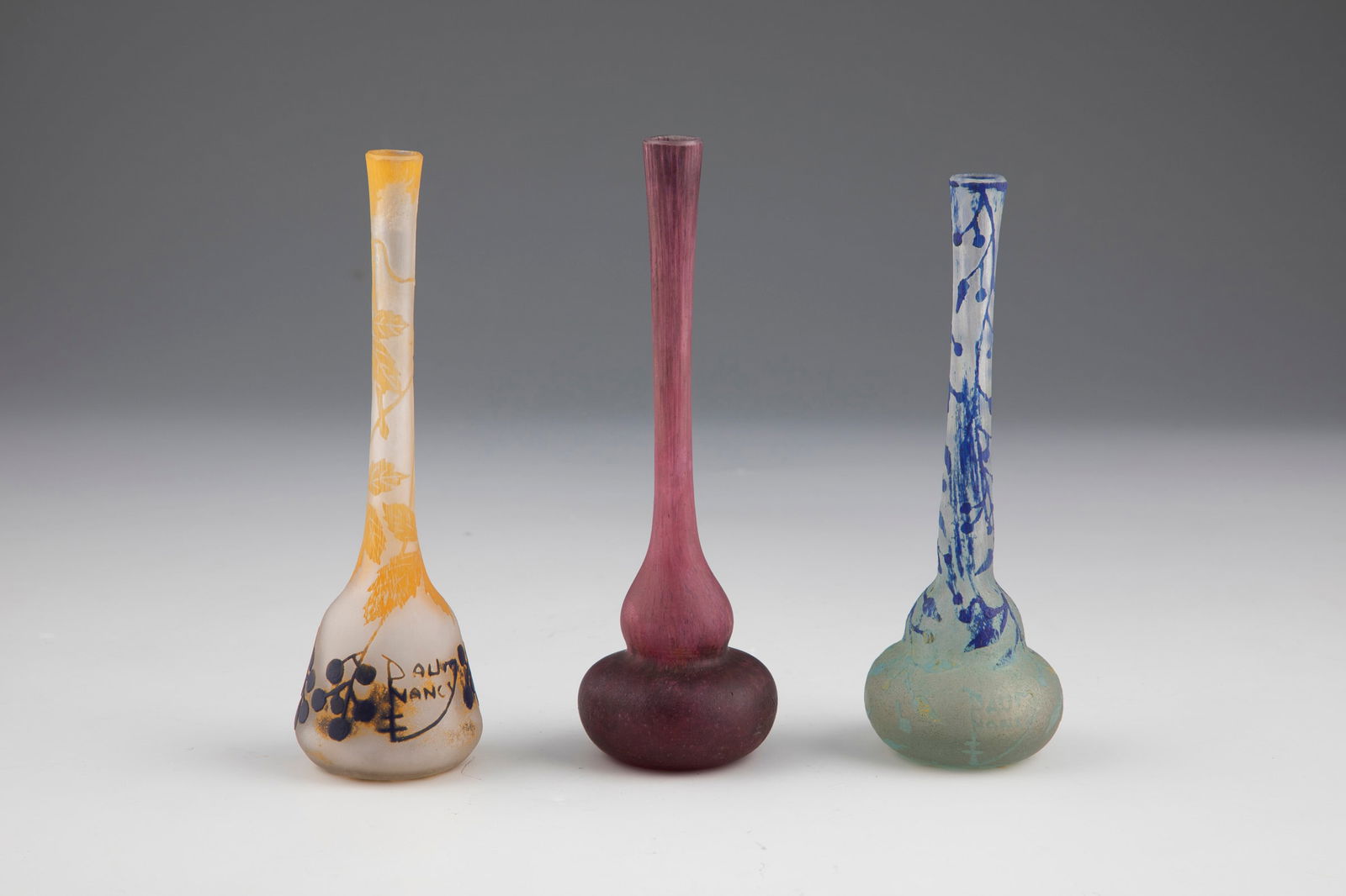 Three small vases: Three small vases Daum Frères, Nancy, c. 1910 Flashed and undercover glass and with multicoloured powder melting. Two vases with an etched decoration in relief all around: flowers and buds with folia