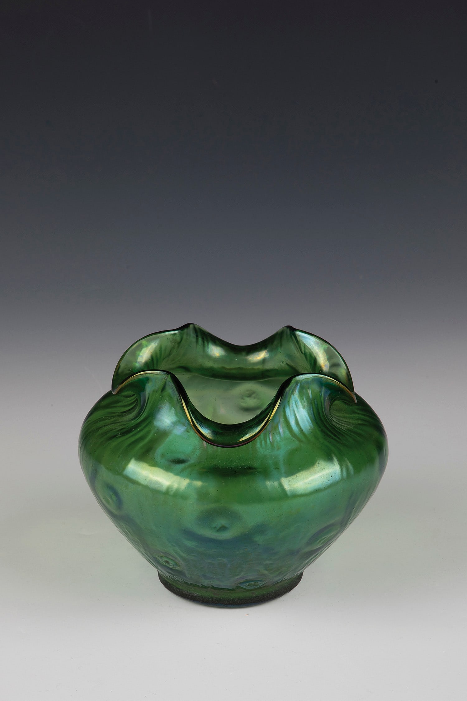 Vase ''Rusticana'': Vase ''Rusticana'' Loetz Wwe., Klostermühle, c. 1899 Green glass, pre-blown in optical form with gnarled structure. Matt iridescent. Muzzle lobed down four times. H. 11 cm.